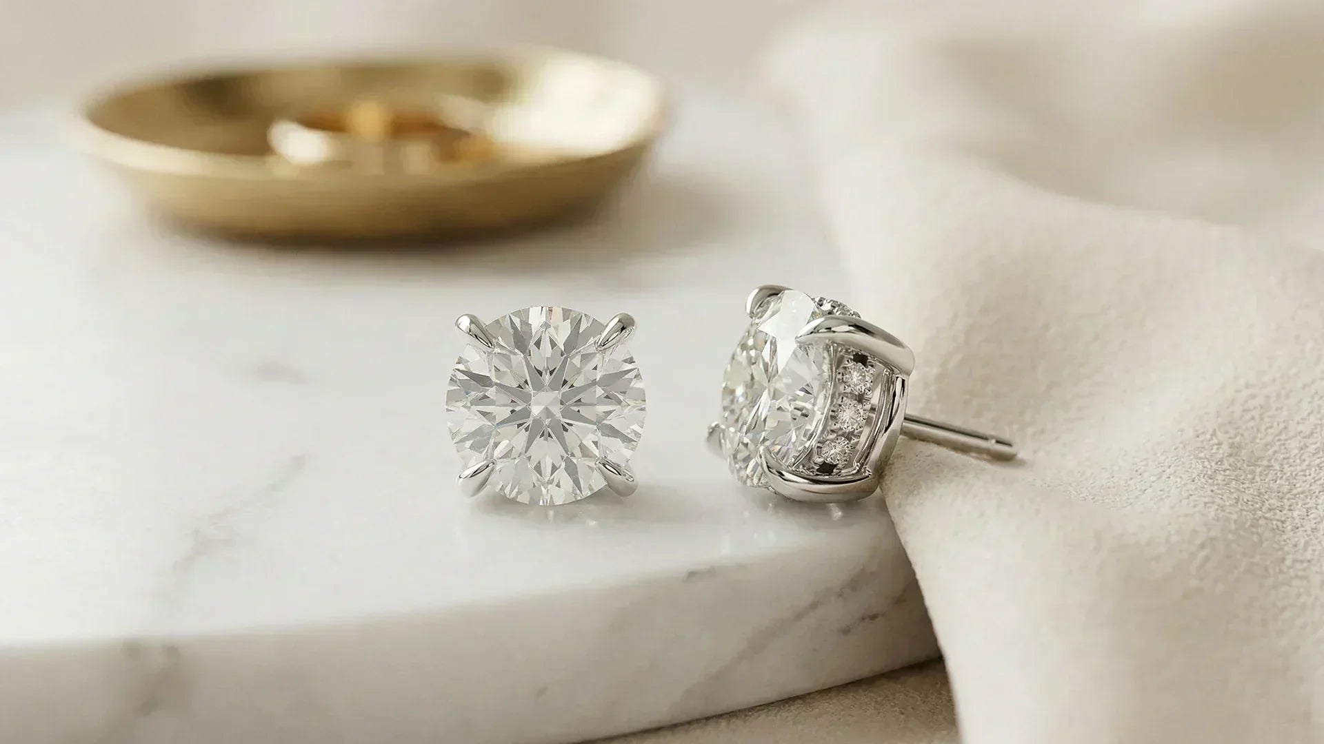Round hidden halo lab-grown diamond studs on marble