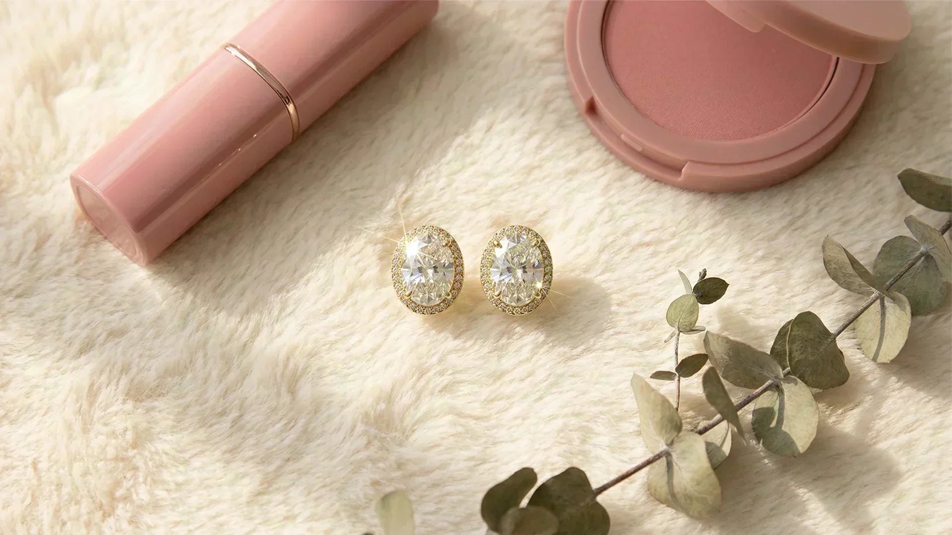 Oval lab-grown diamond stud earrings in gold on cream fur cloth flat lay