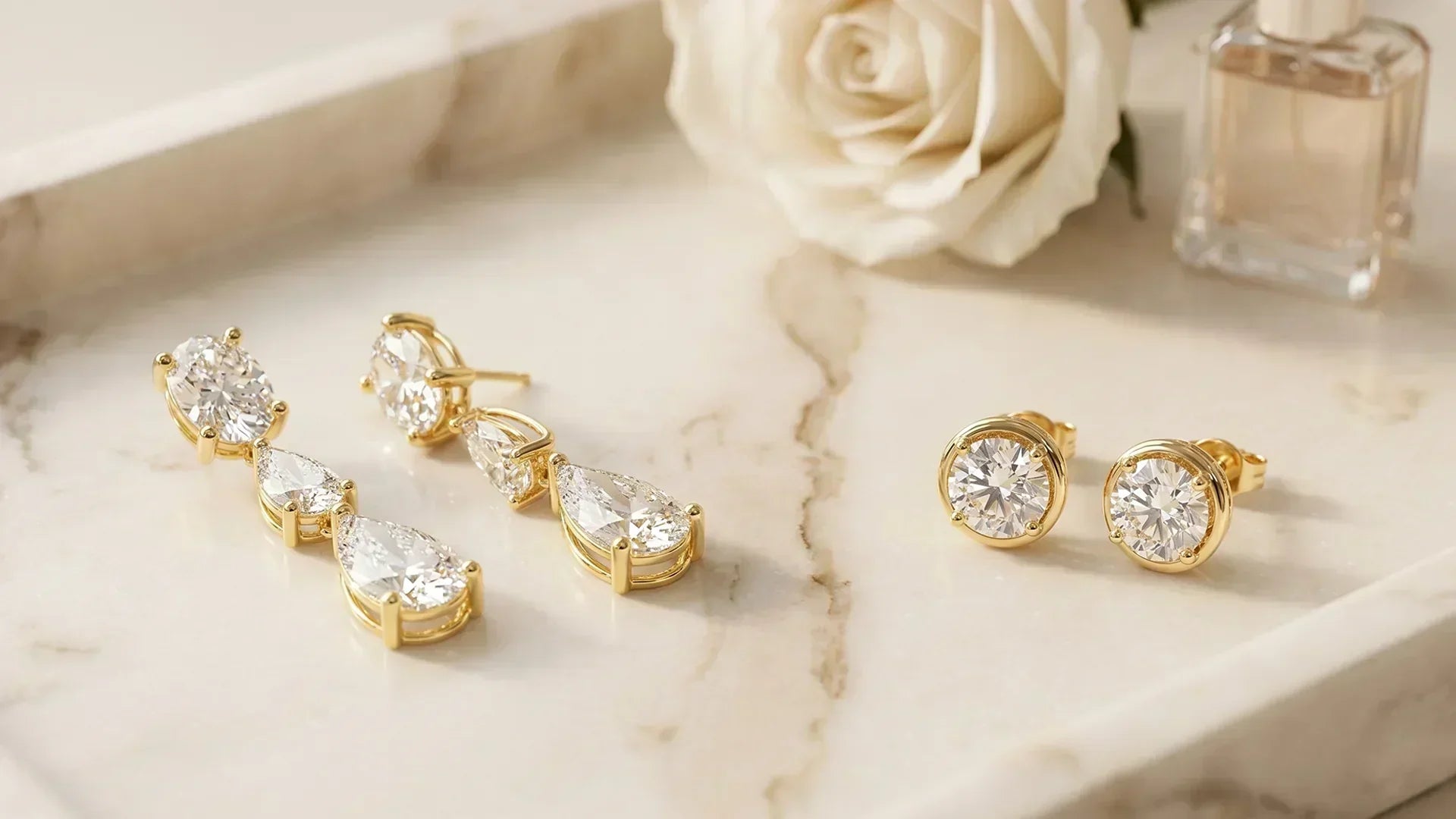 Lab-grown diamond drop earrings and stud earrings on marble tray