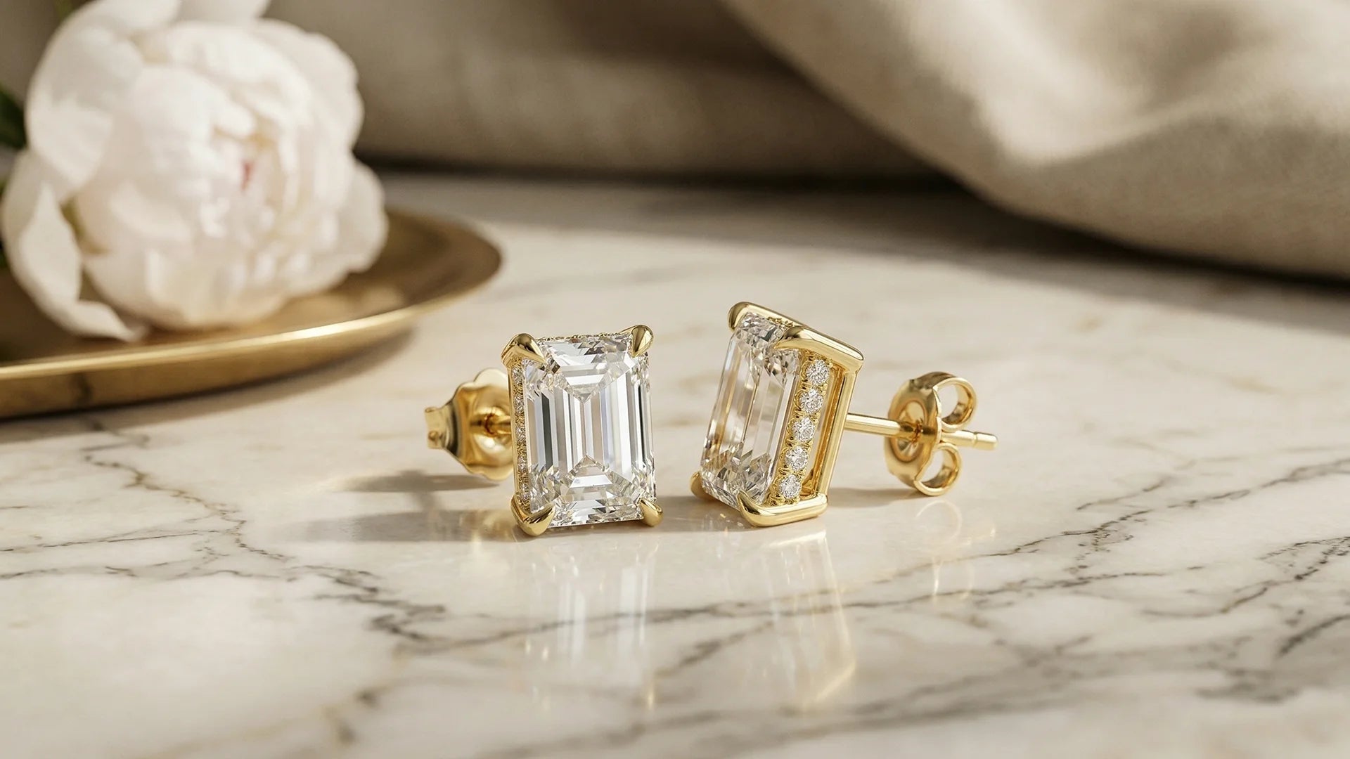 Emerald hidden halo lab-grown diamond studs on cream marble 