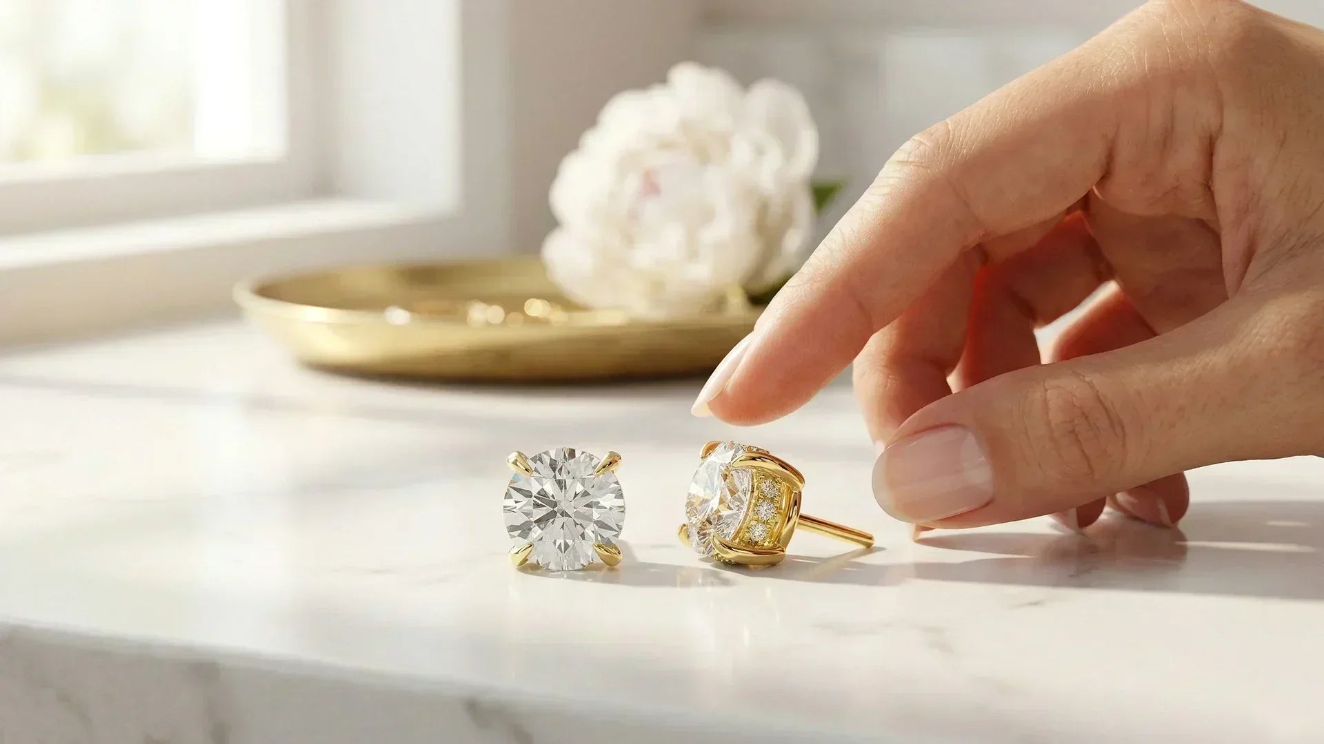 Woman reaching for round hidden halo diamond studs on marble vanity