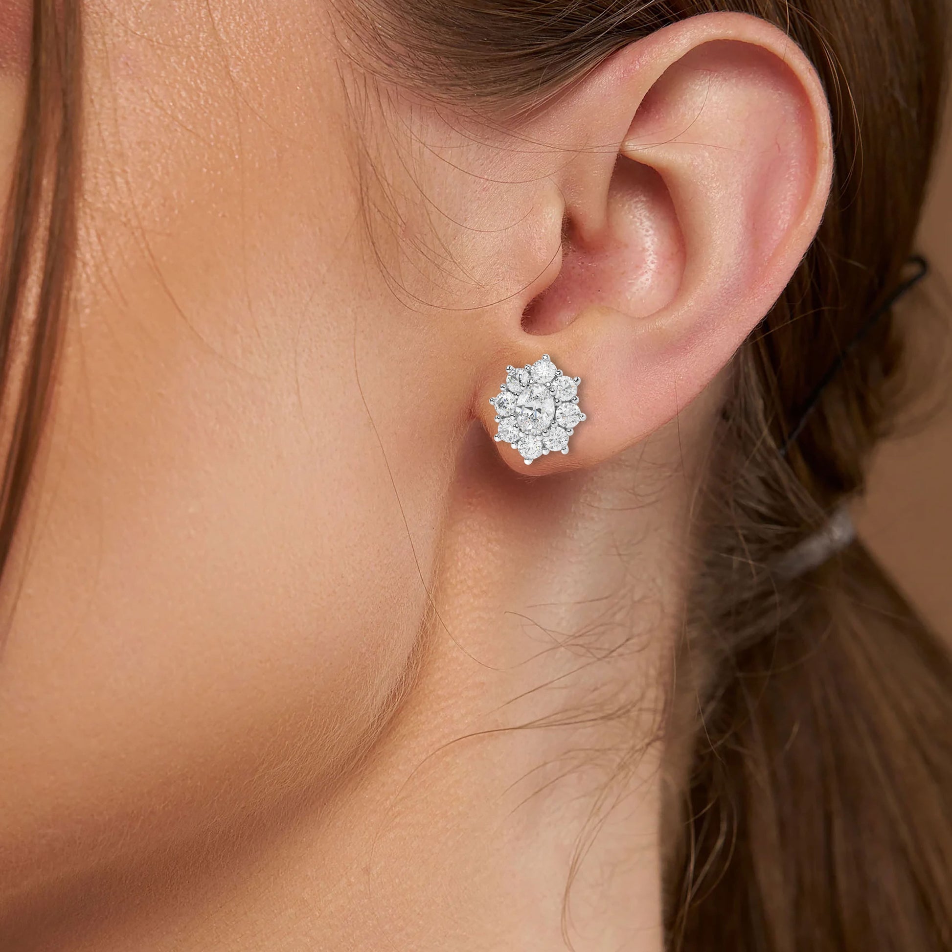 Model wearing white gold lab-grown diamond halo stud earrings with oval center and radiant round diamond halo, side ear view, timeless diamond accessories