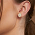 Model wearing yellow gold lab-grown diamond halo stud earrings featuring oval center stone and sparkling round diamond cluster, side profile view, elegant diamond jewelry