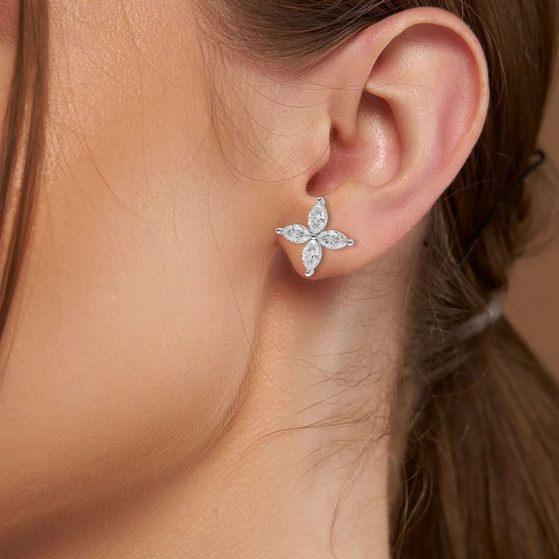 White gold lab grown diamond marquise floral earrings worn on woman's ear close-up model shot showing sparkling four petal design