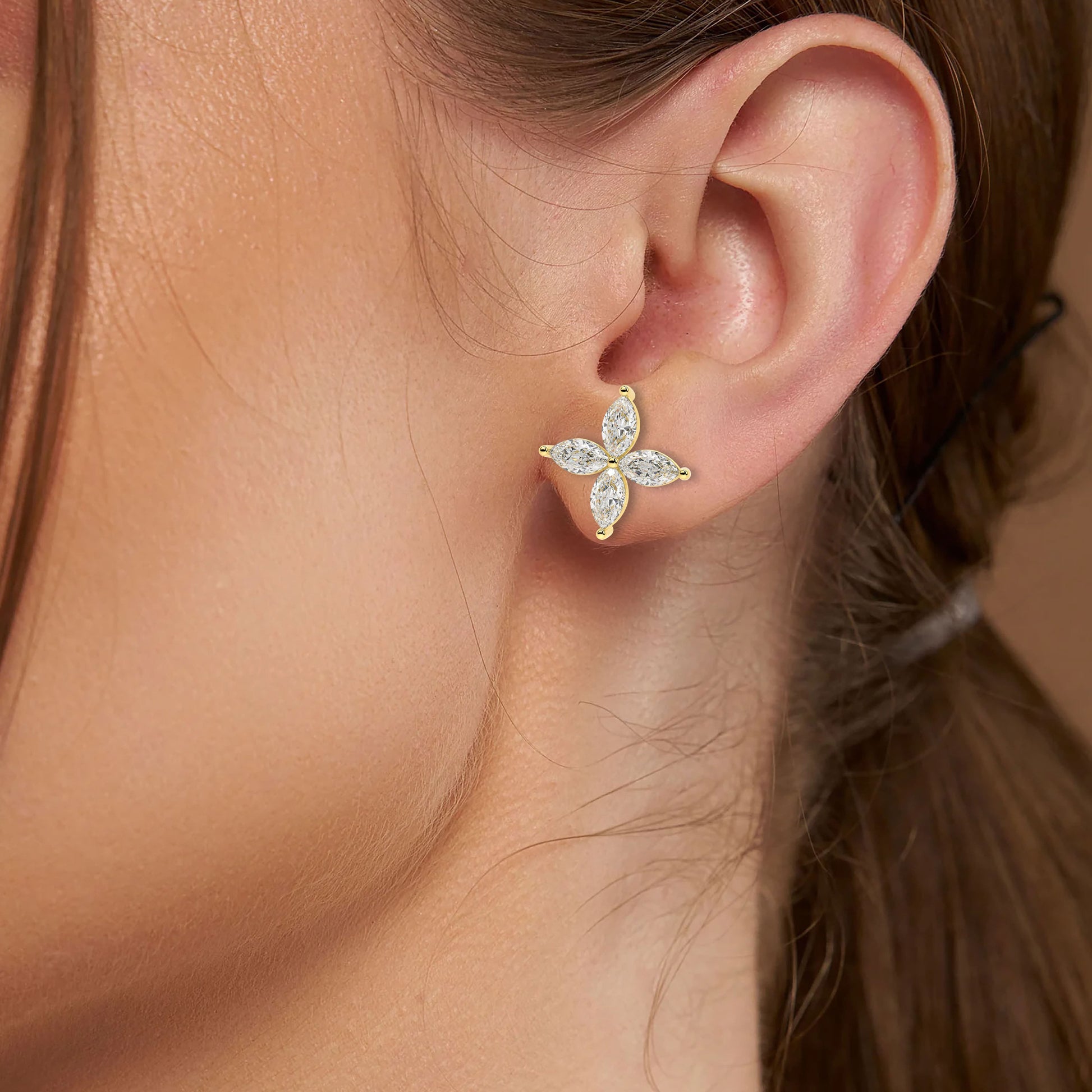 Yellow gold lab grown diamond marquise floral earrings worn on woman's ear close-up model shot showing sparkling four petal design