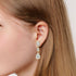 Model wearing yellow gold lab-grown diamond round solitaire stud earrings on ear, side profile view, sparkling single diamond design, elegant classic studs