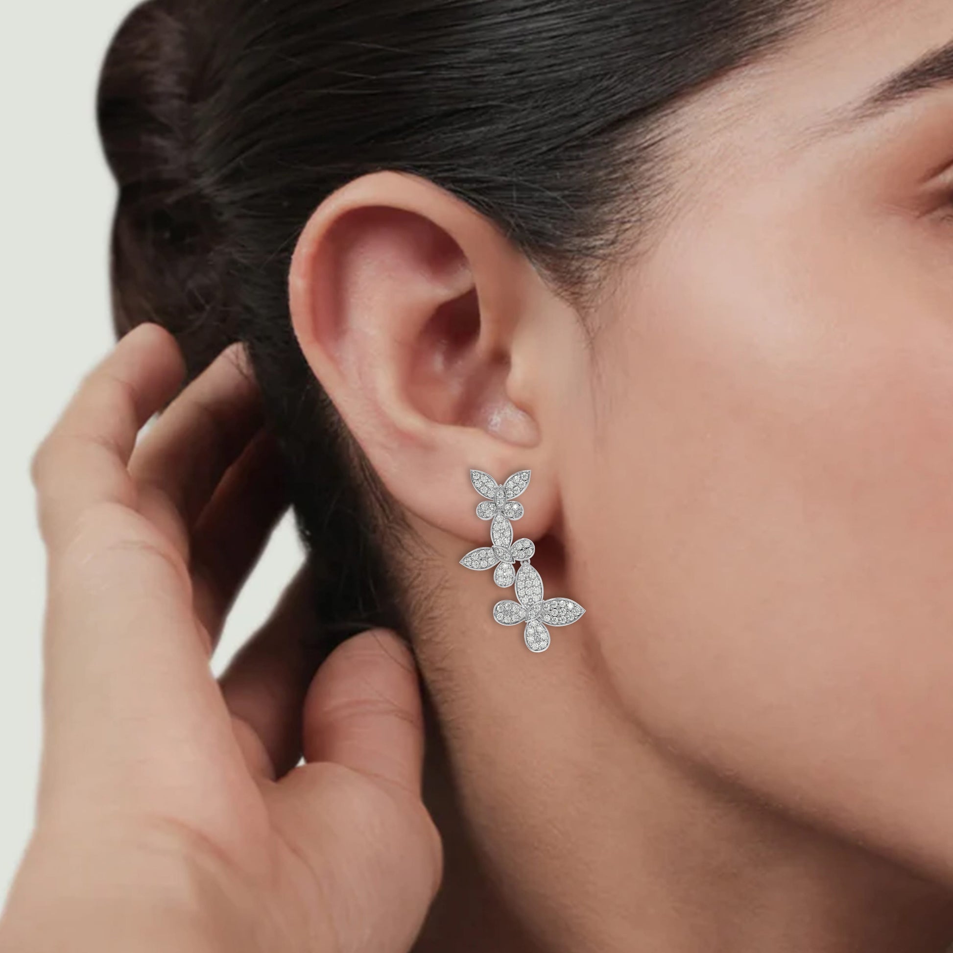 Model wearing white gold lab-grown diamond floral vine stud earrings on ear, side view, radiant marquise and pear Pavé design, timeless luxury diamond accessories