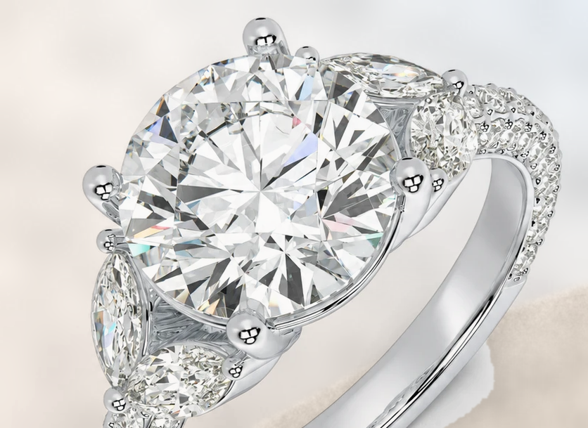 Round diamond engagement ring with pear-shaped side stones and pavé band